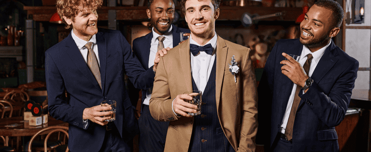 a group of groomsmen smiling and cheering on groom
